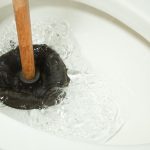 Plumbing expert from Jim Wagner Plumbing unclogging toilet.
